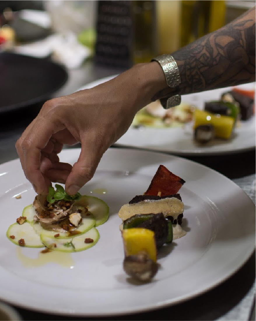 The hand of Mercedes Cerouno adding the finishing touches to a plate of food.