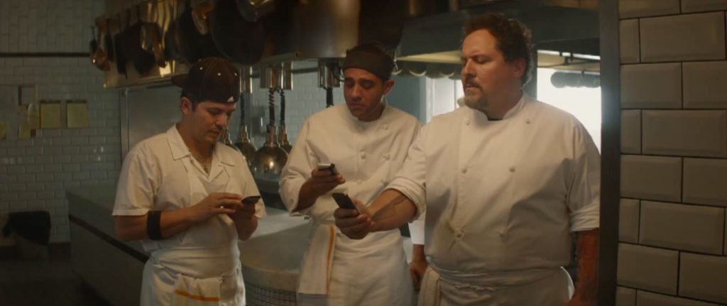 Three chefs holding smart phones in the kitchen