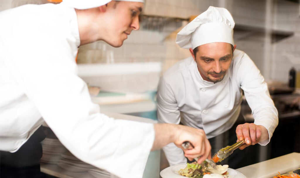 Two chefs working on plating a dish to illustrate do you need a degree to be a chef.