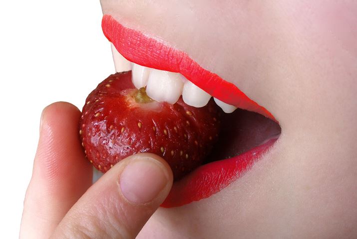 Woman putting a strawberry in her mouth