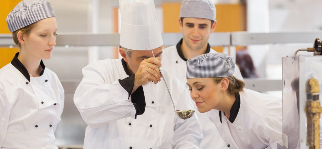 A picture of a chef and some students in the kitchen to illustrate how long is culinary school