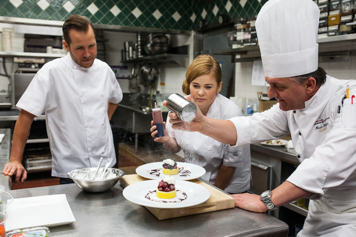 Chef teaching his students on final prep for deserts