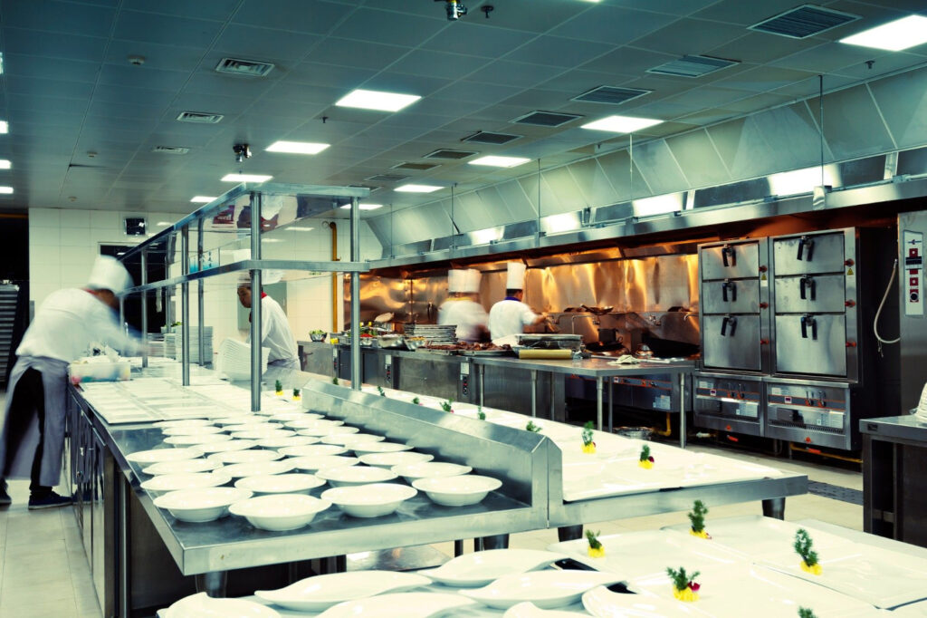 A largely empty kitchen with a few chefs preparing food to illustrate the hierarchy of chefs.